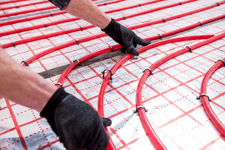 Plumber installing radiant heating coils in floor